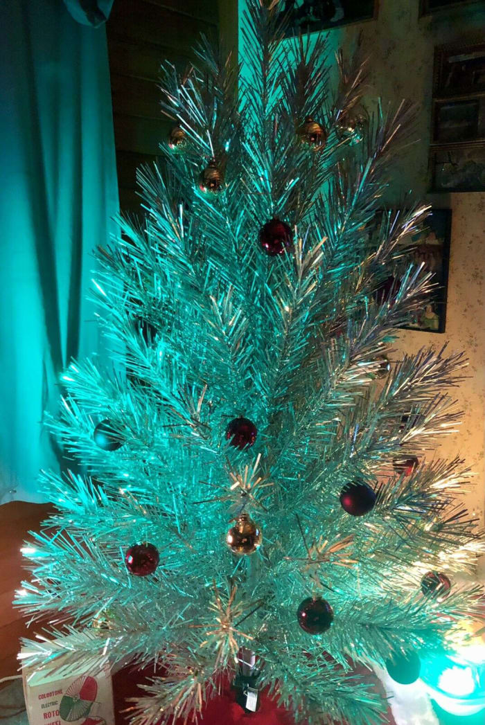 The 94-branch vintage 6-foot Evergleam lit up in teal, with the aid of a color wheel.