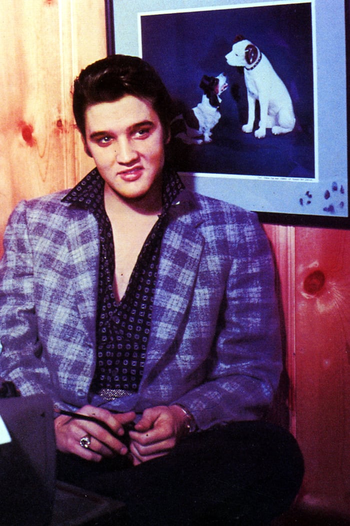 Elvis favored coats and jackets in unexpected colors, like this purple one, and with an open shirt, of course. Although the shirt has a clashing pattern, the future King works it. This photo is circa 1956-1957.